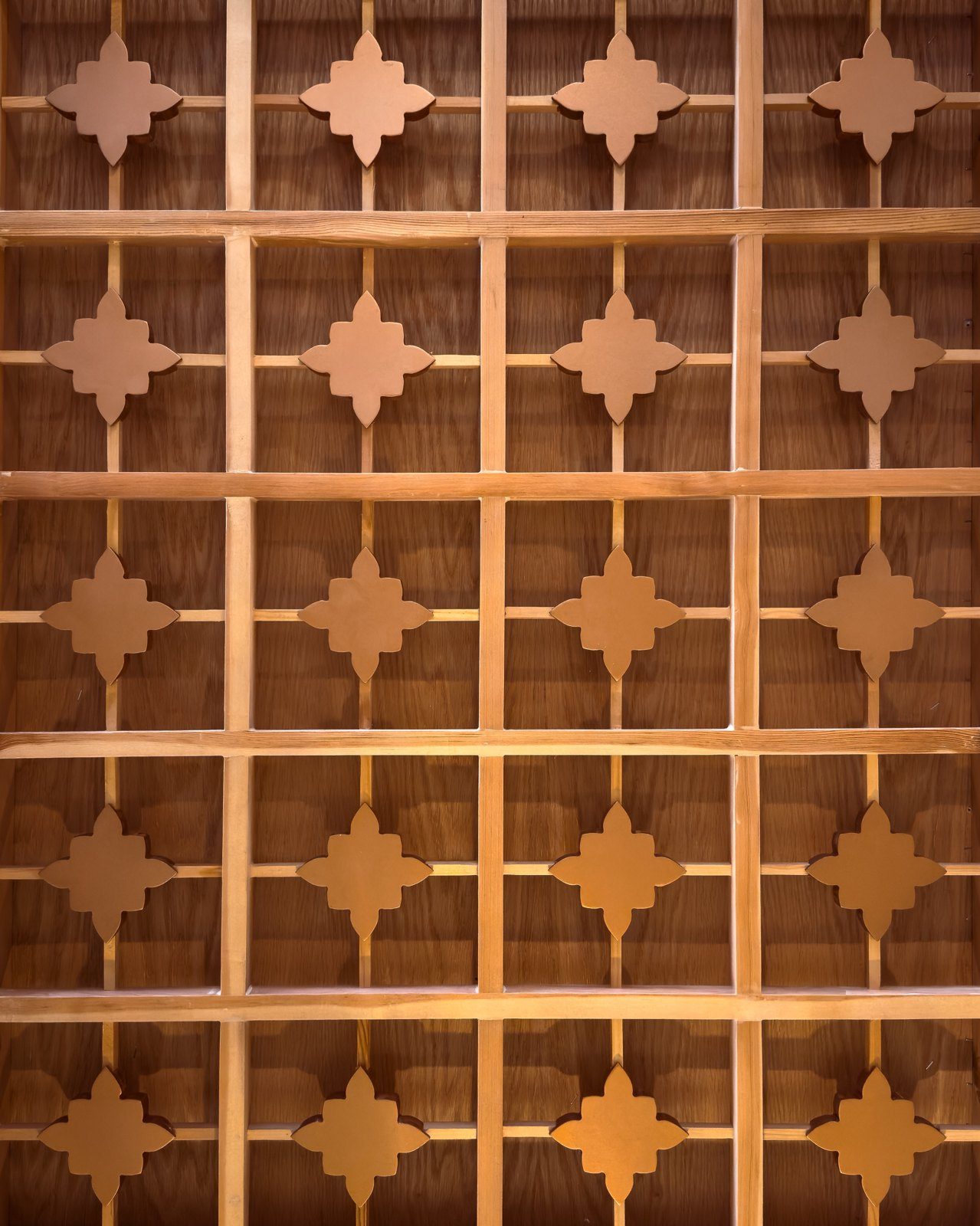 A carved wooden screen in a star pattern, lit warm