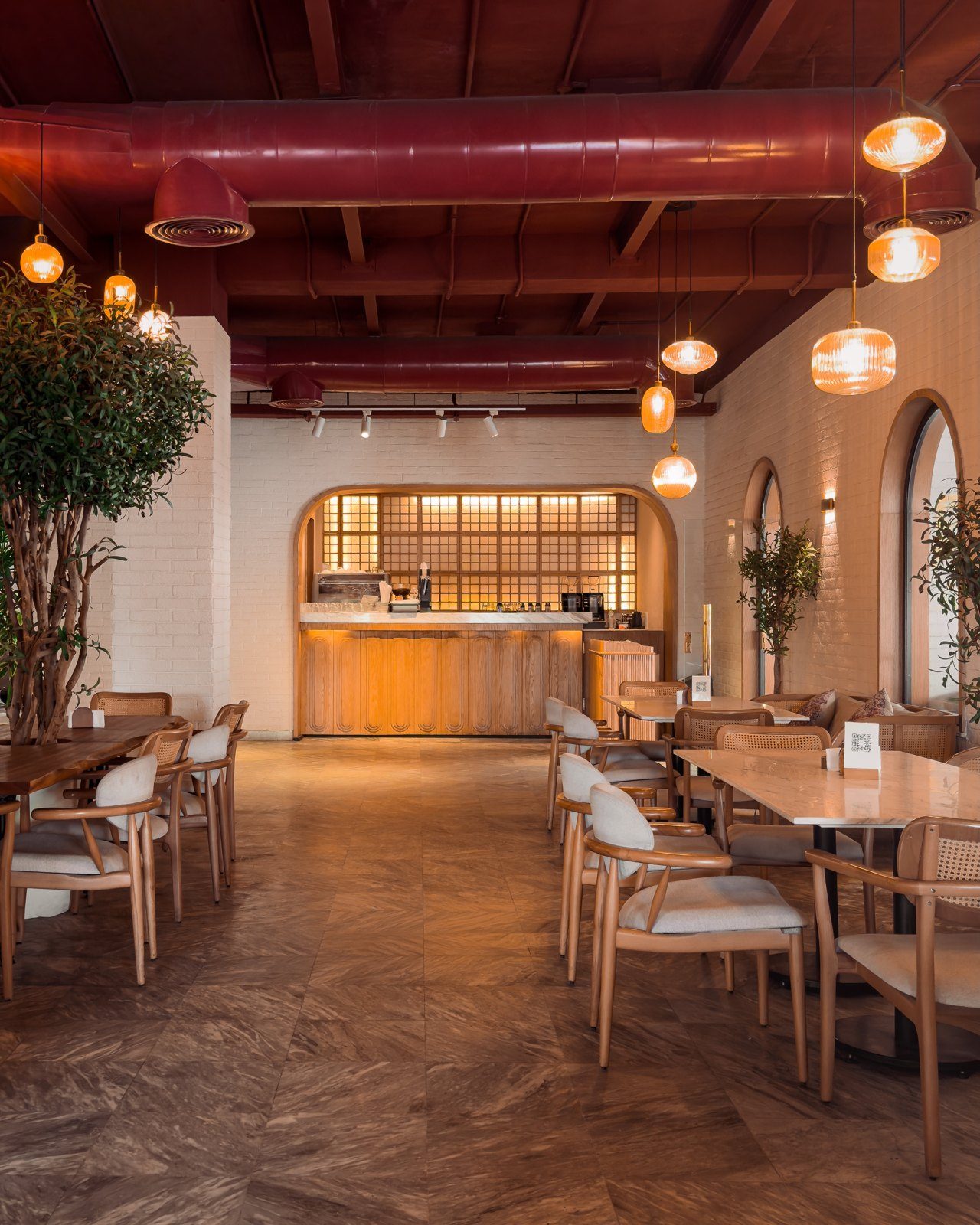 The dining room: exposed red brick ceiling, glass pendant lamps, arches and a herringbone parquet floor